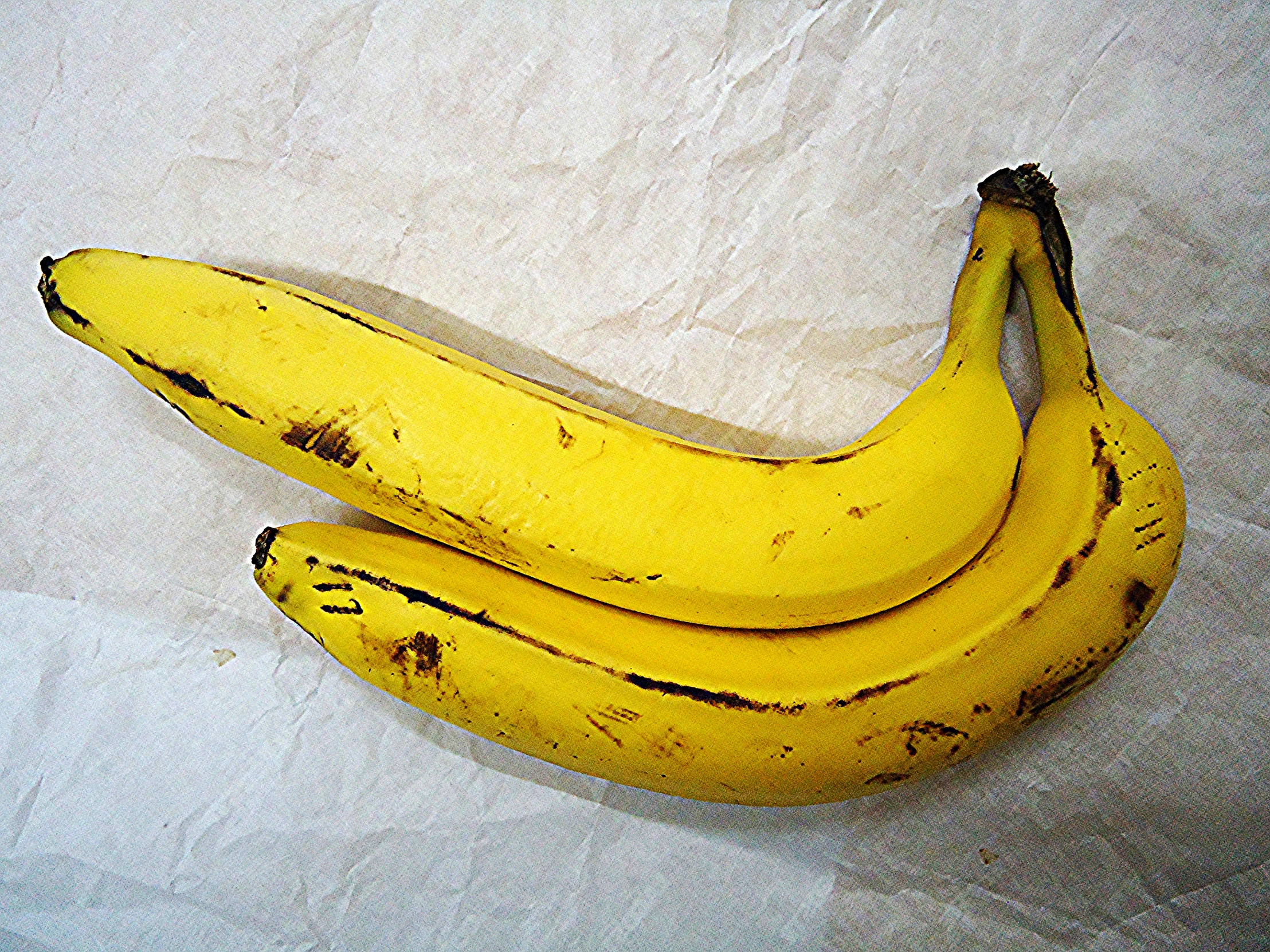 a pair of bananas placed on a white surface