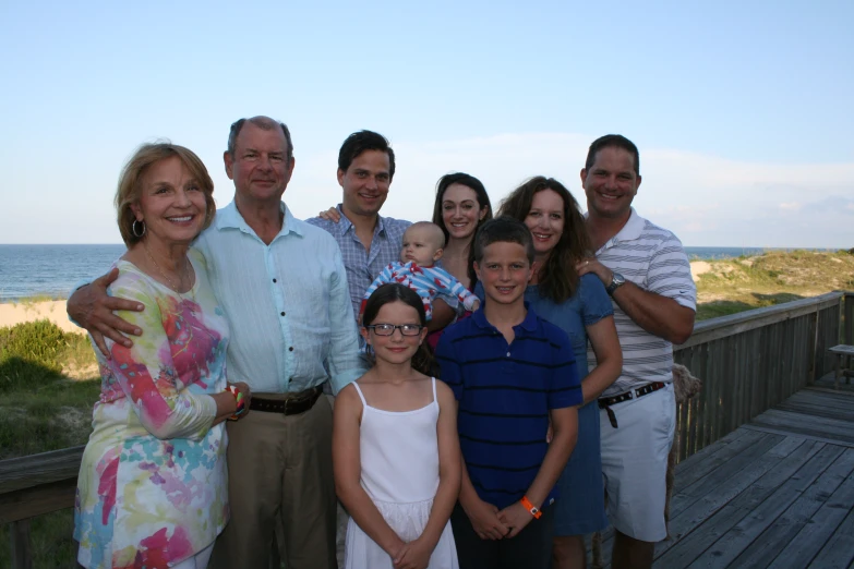 a large family is smiling in front of the beach