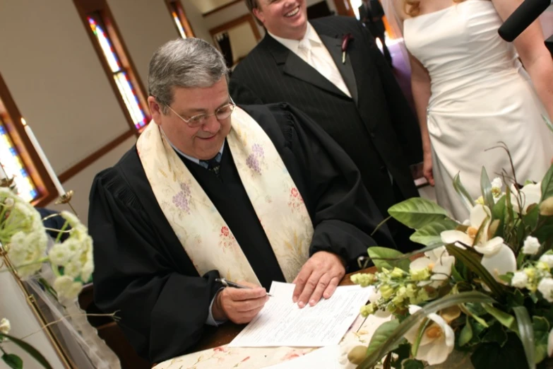 a priest in black robe signing wedding register