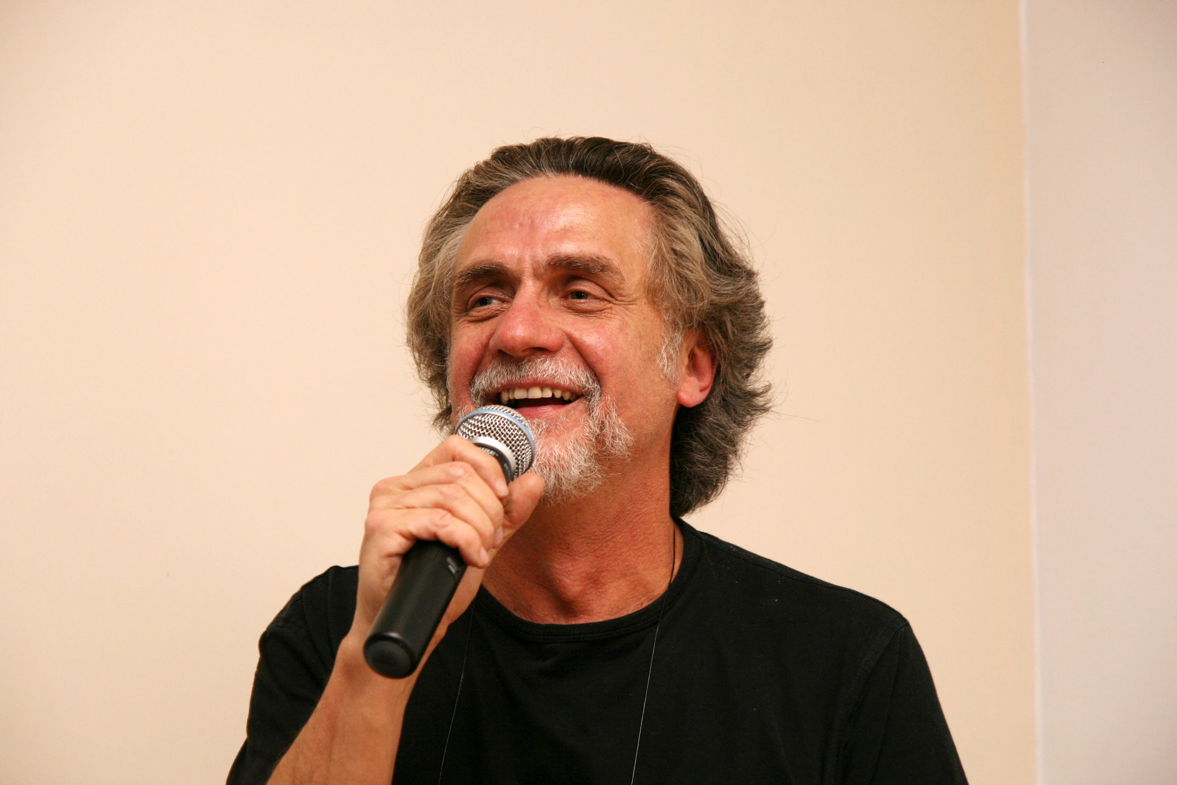 an older man holding a microphone to his left