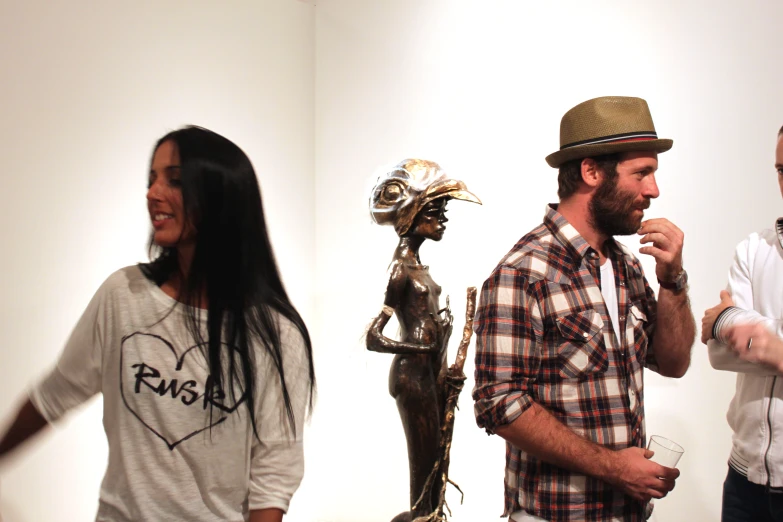 a man stands among a group of three other people, one in plaid shirt and hat