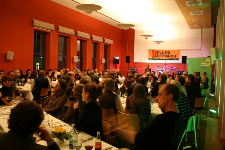 a room full of people sitting at tables next to two red wall doors