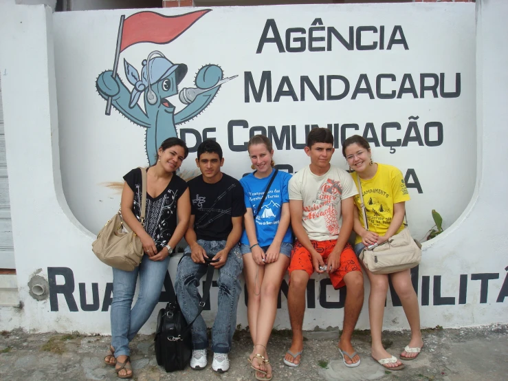 four young people sitting on a rock wall in front of a sign with the words, argentina mandarinacaru comidaca