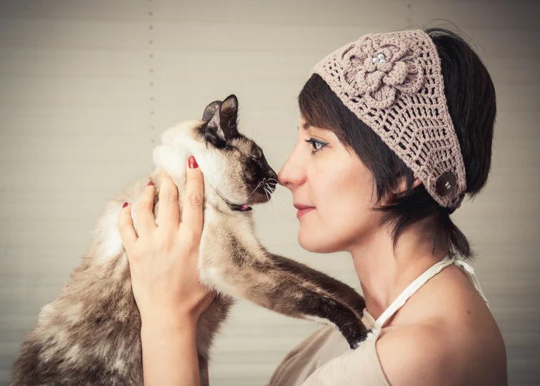 a woman is kissing her cat in a hat
