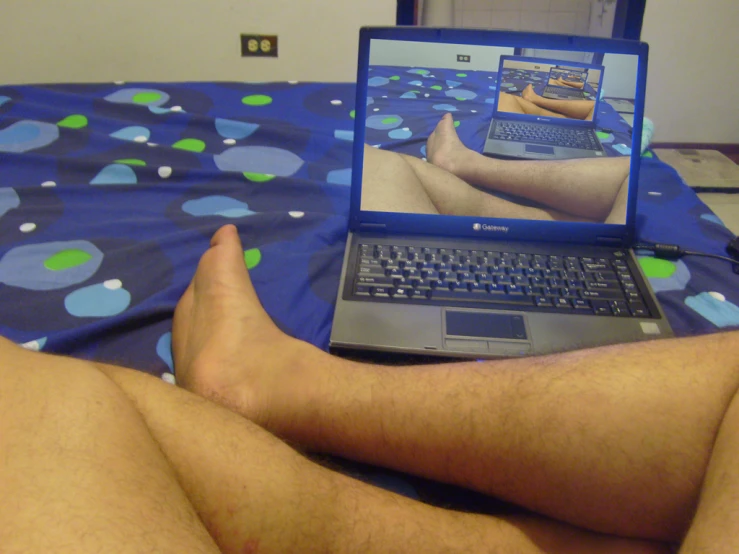 man on his bed with a laptop displaying images on the screen