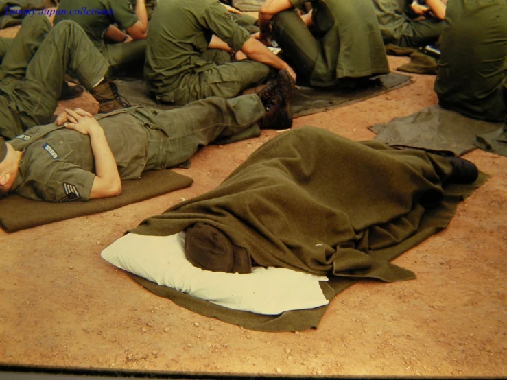 a group of men with green army clothing are lying on the floor