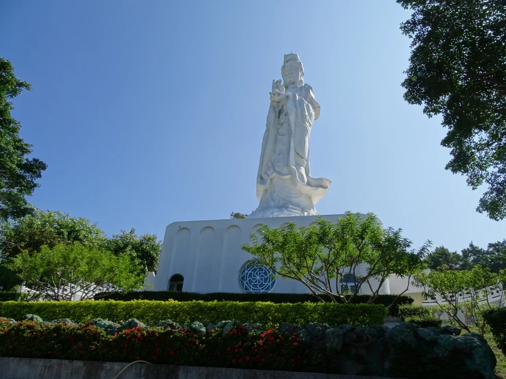 a tall statue next to some very pretty bushes