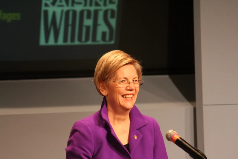 the woman in purple is speaking at a podium