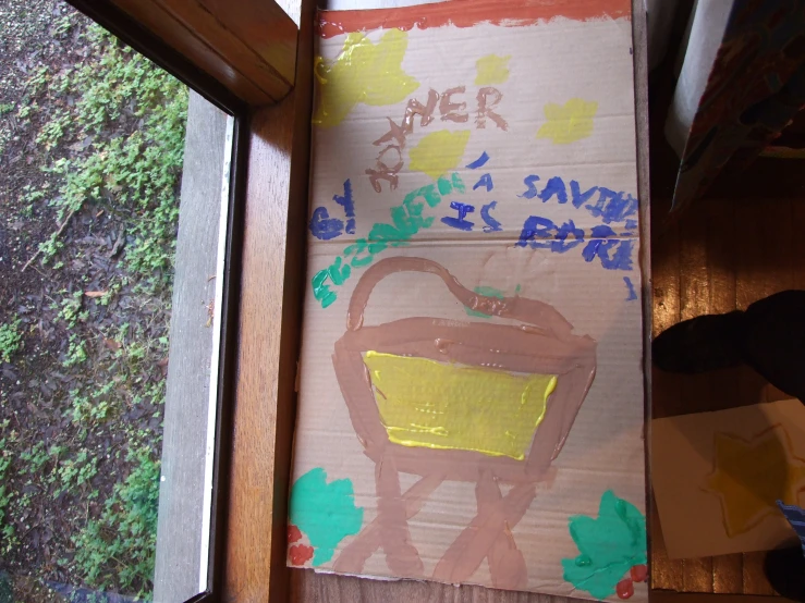 a cardboard box sitting next to a window covered in green and orange graffiti