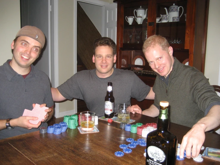 a group of three men standing over a wooden table