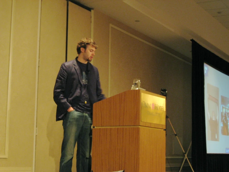 a man standing at a podium in front of a projection screen