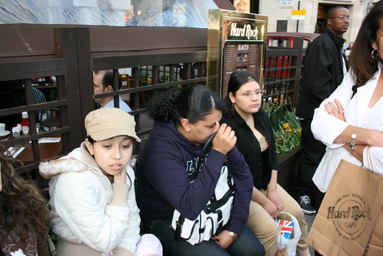 people sitting in front of a book shop on the sidewalk