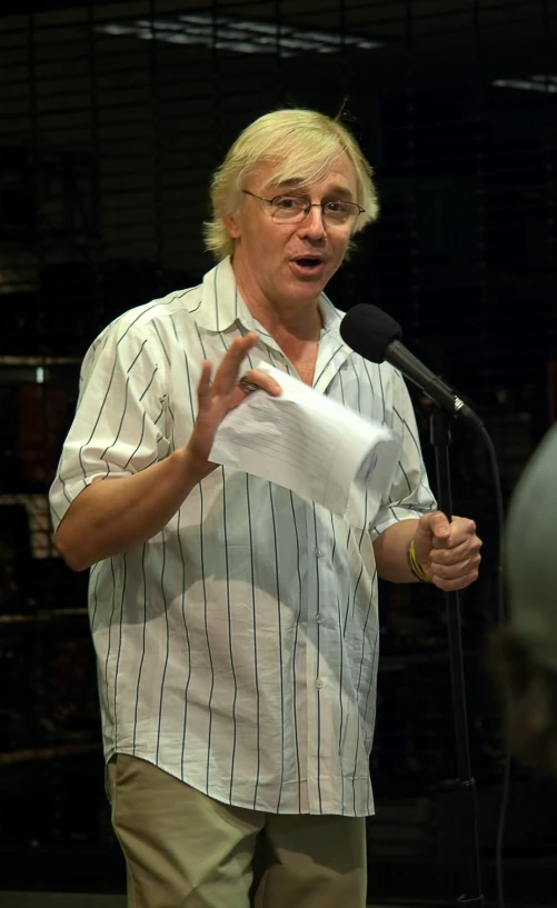 man with blond hair in a striped shirt speaking to a group