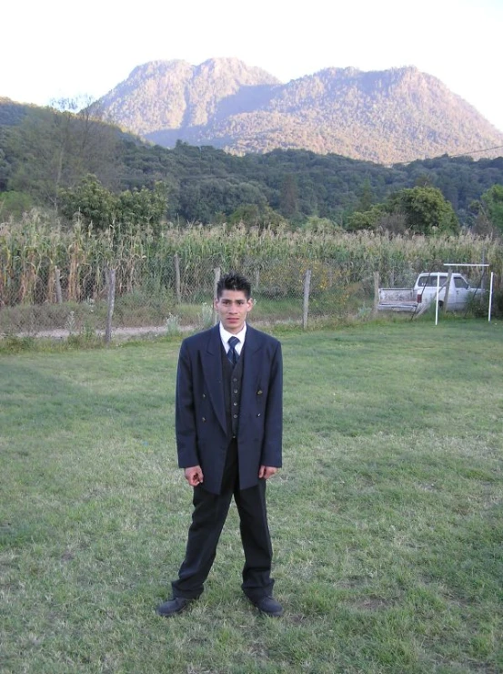 a man in suit and tie standing in the grass