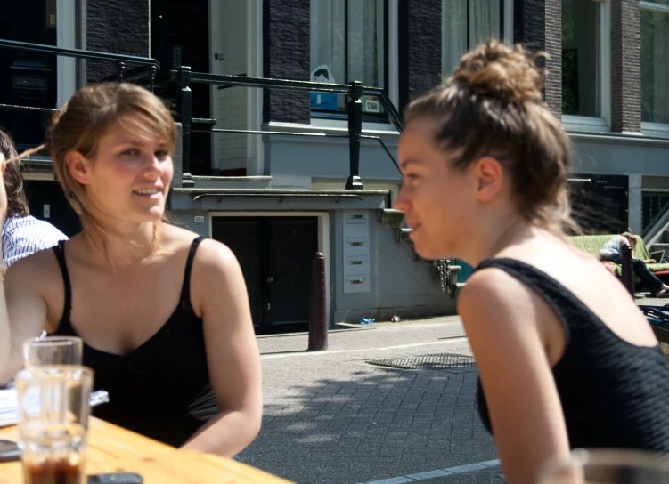 four young women seated around a wooden table talking