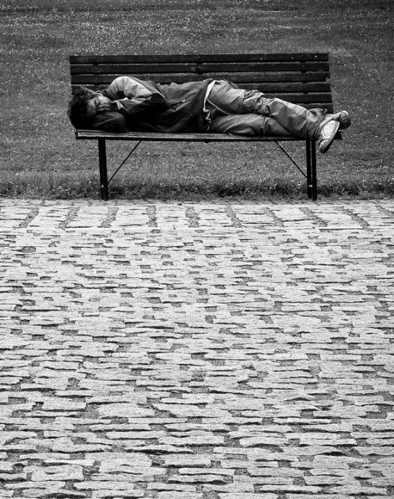 black and white po of a person laying on a bench