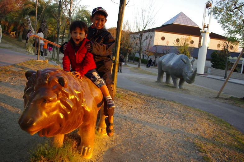the children are sitting on the metal bull sculpture
