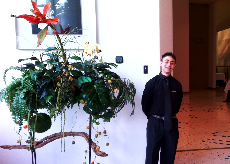 a man wearing a black tie standing next to some trees