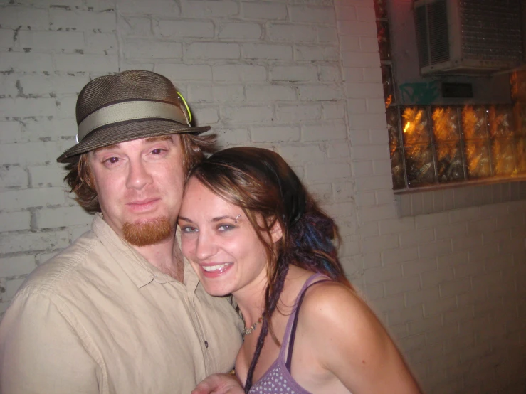 man and woman standing together, next to a brick wall