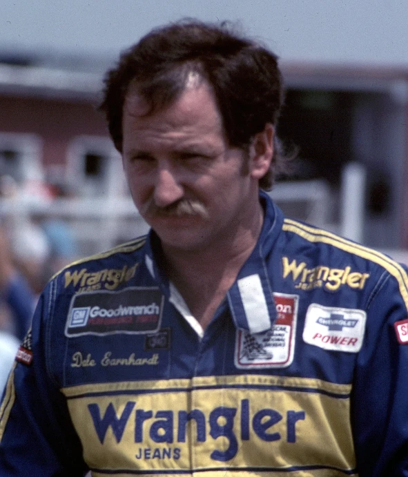 a man with a moustache walking around a race track