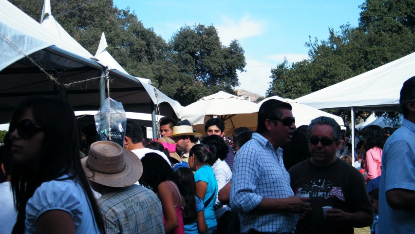 a crowd of people standing around tents at a farmers market