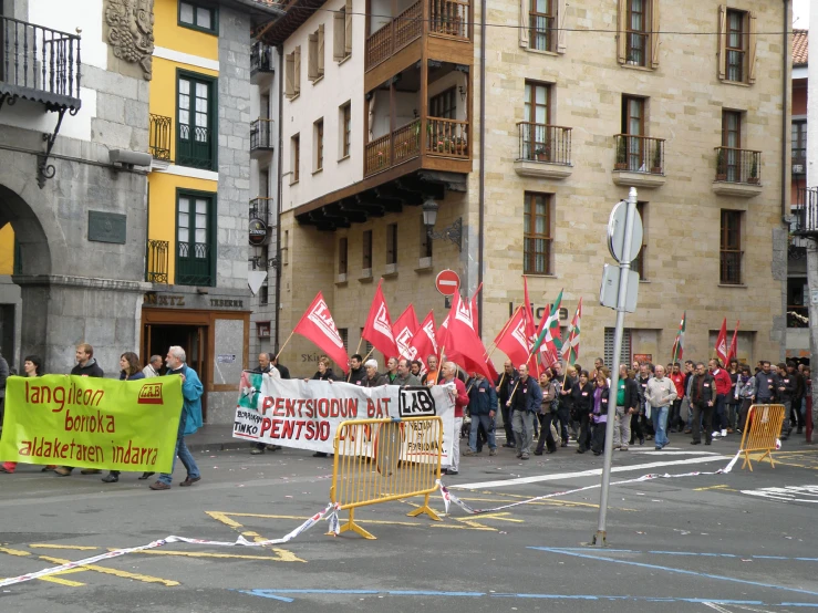 a large group of people with flags stand in a city street