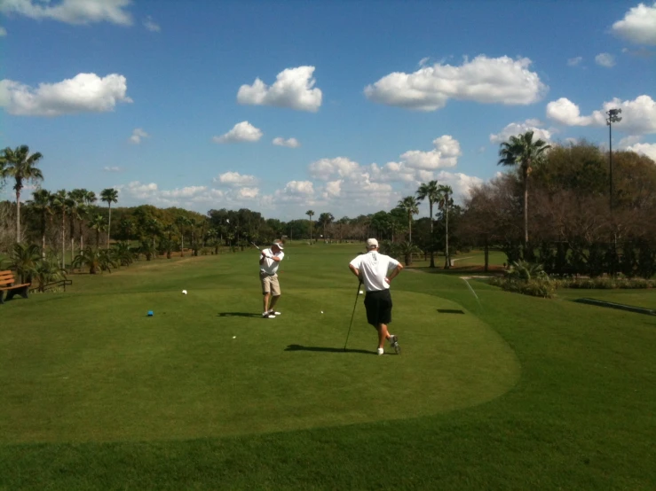 two men practice golf on a beautiful sunny day