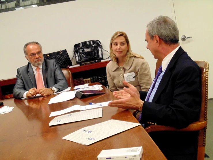 four people sitting around a wooden table having a meeting