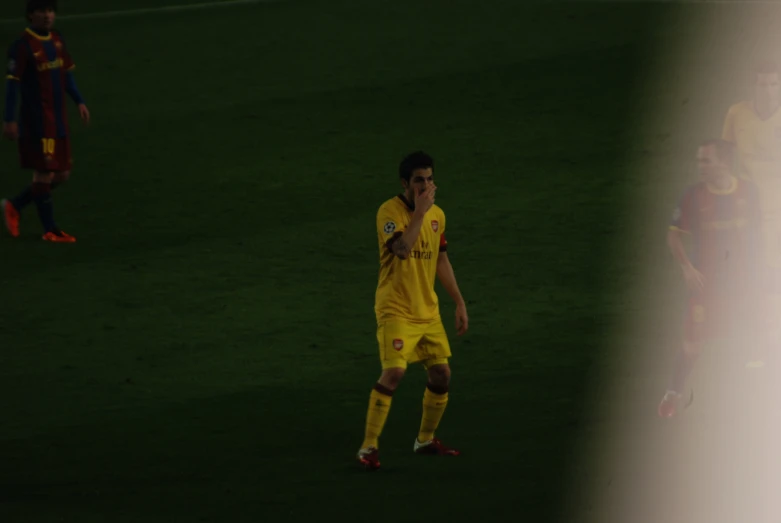 a man in yellow jersey in field with people looking on