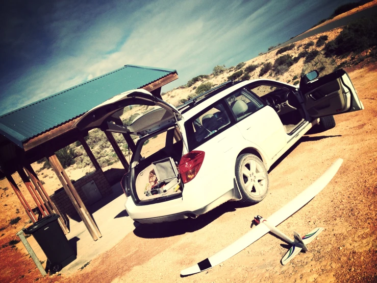 an open car door on the sand with it's hood open