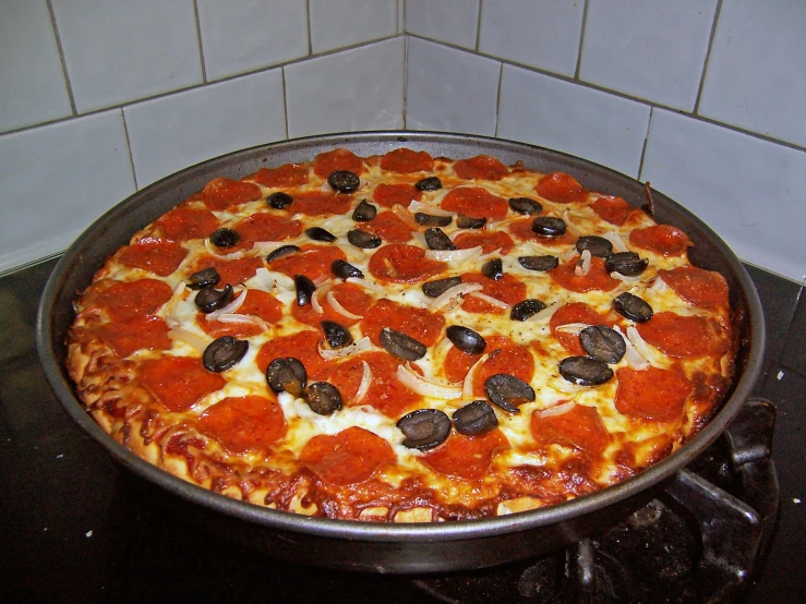 an oval pepperoni and mushroom pizza is in a pan on the stove