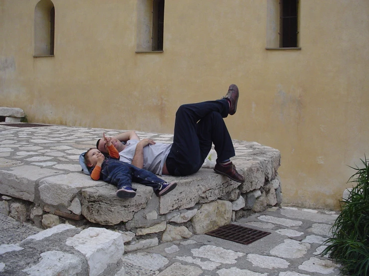 two men lay on stone steps as one walks