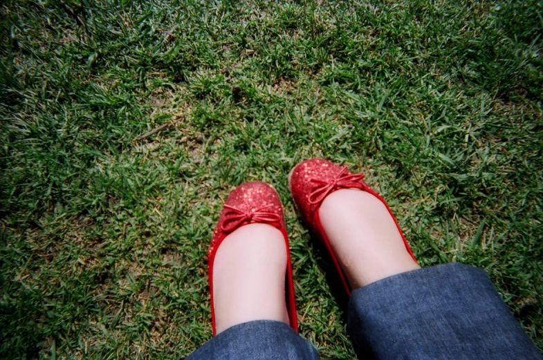 the legs of a person with red shoes are laying in the grass