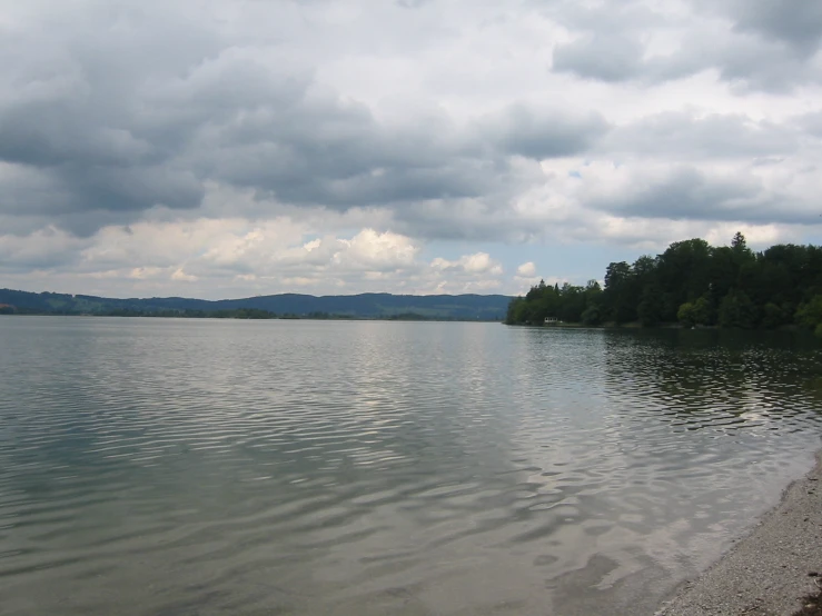 some white clouds a body of water and trees