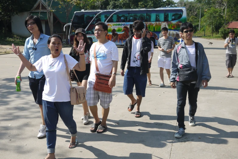 a group of people walk together in front of a bus