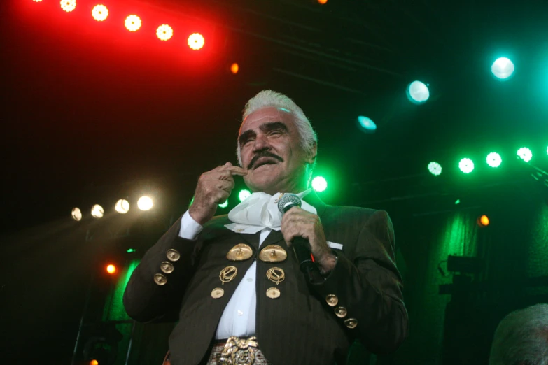 man in gold and green suit speaking into a microphone