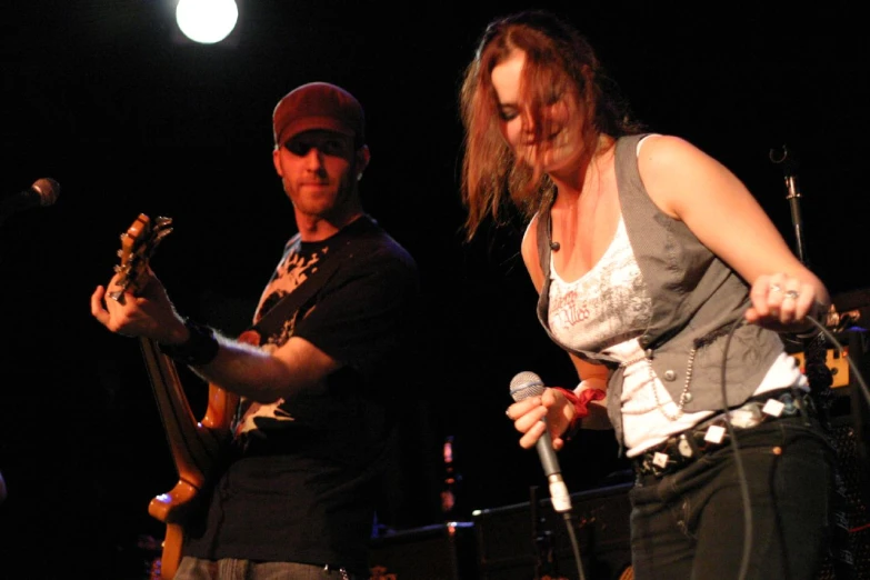 a man and woman singing into microphones at a concert