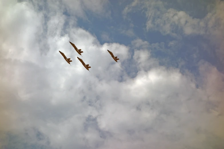 three airplanes flying thru a cloudy sky with one plane high in the air