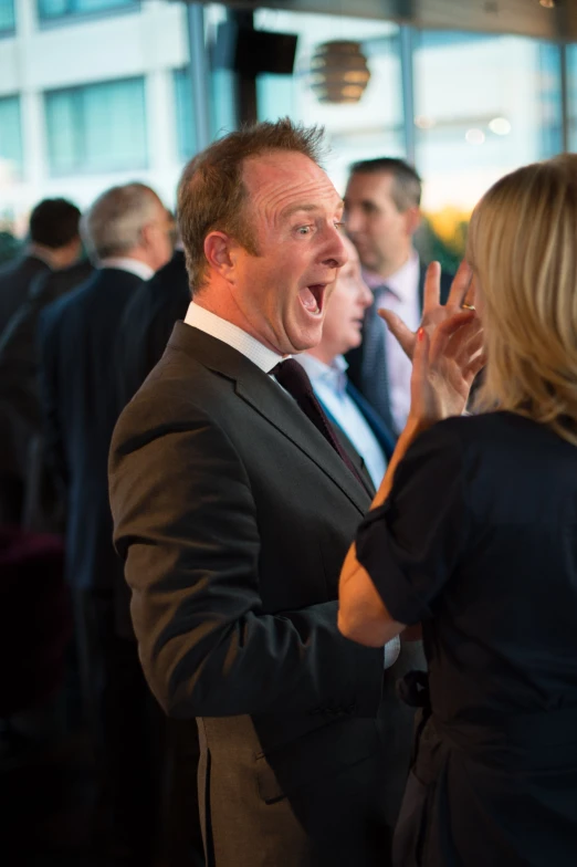 a man talking to two woman in suits