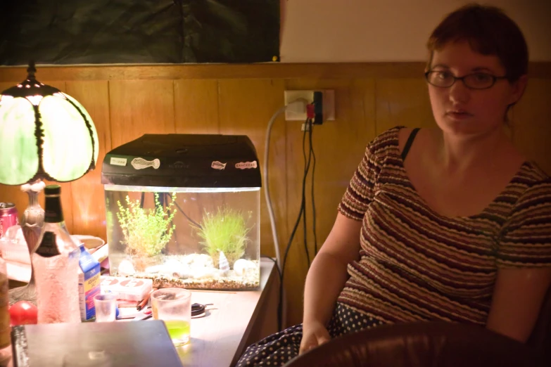 a woman sitting on a brown chair in front of an aquarium