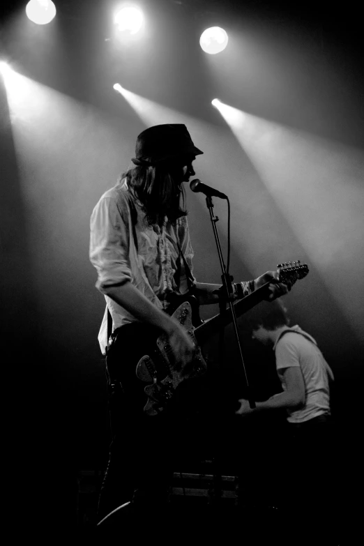 a man standing in front of a microphone holding an electric guitar