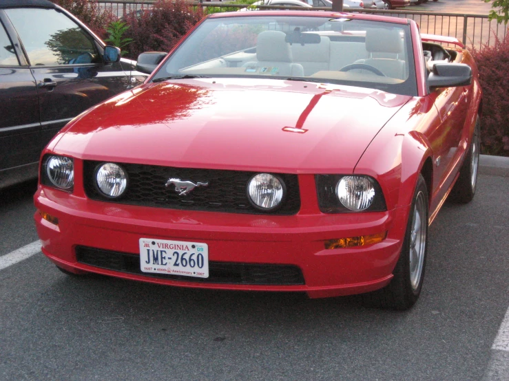 a red mustang convertible car is parked in a parking lot