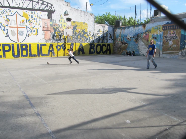 two skateboarders do different stunts in front of a painted wall