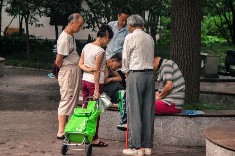 men and women standing around talking by a man with a green piece of luggage