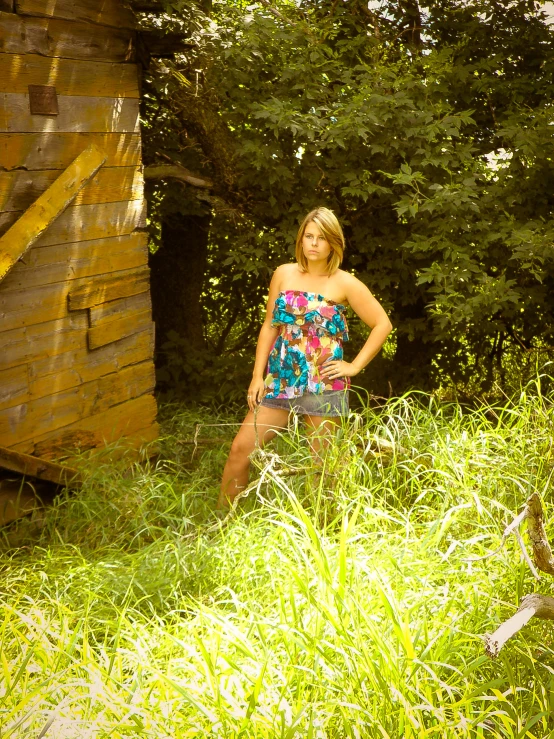 a girl wearing a flowered blouse and short shorts in the grass