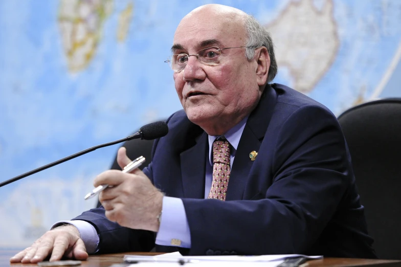 an older man sitting in front of a microphone holding a pipe