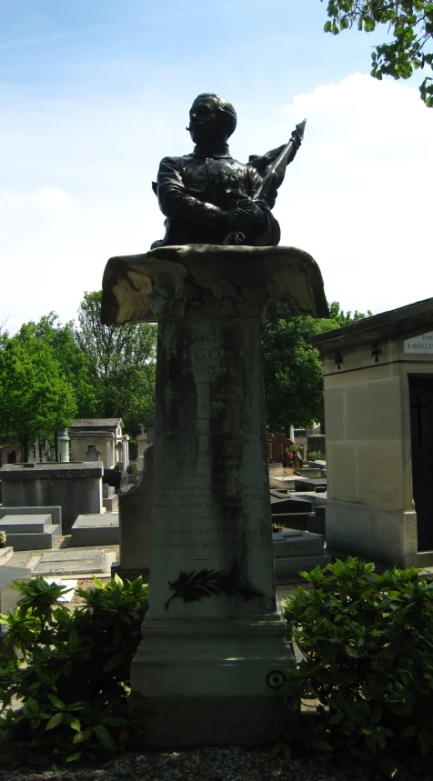 a statue on the side of a road with bushes in front