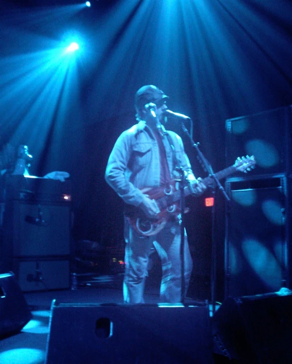 a man singing into a microphone with his guitar