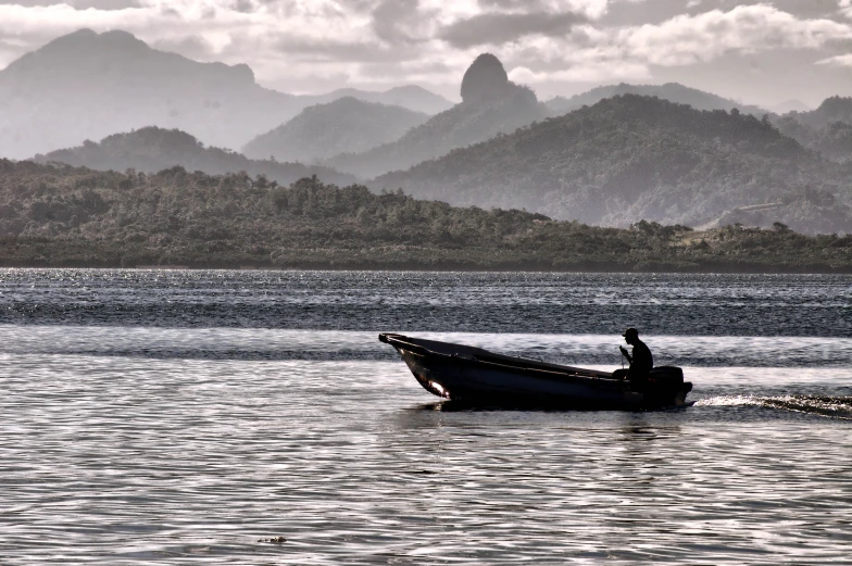 a man sitting in a small boat in a bay