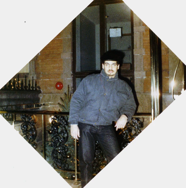 a man wearing a hat and jacket walking in front of a building